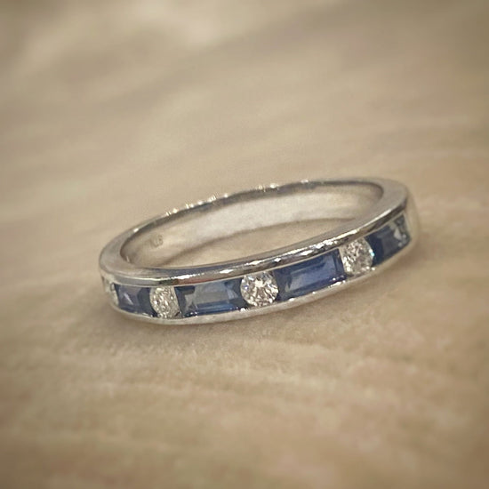 Photo of Blue Sapphire Baguette and Diamond Band in a decorative scene, designed by , available at Plumb Gold & Plumb Silver