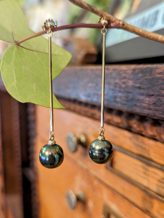 Photo of Tahitian Pearl Long Drop Earrings in a decorative scene, designed by , available at Plumb Gold & Plumb Silver