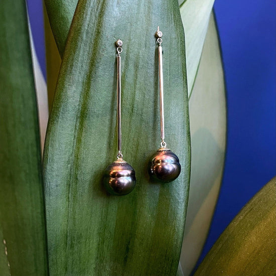 Photo of Tahitian Pearl Long Drop Earrings in a decorative scene, designed by , available at Plumb Gold & Plumb Silver