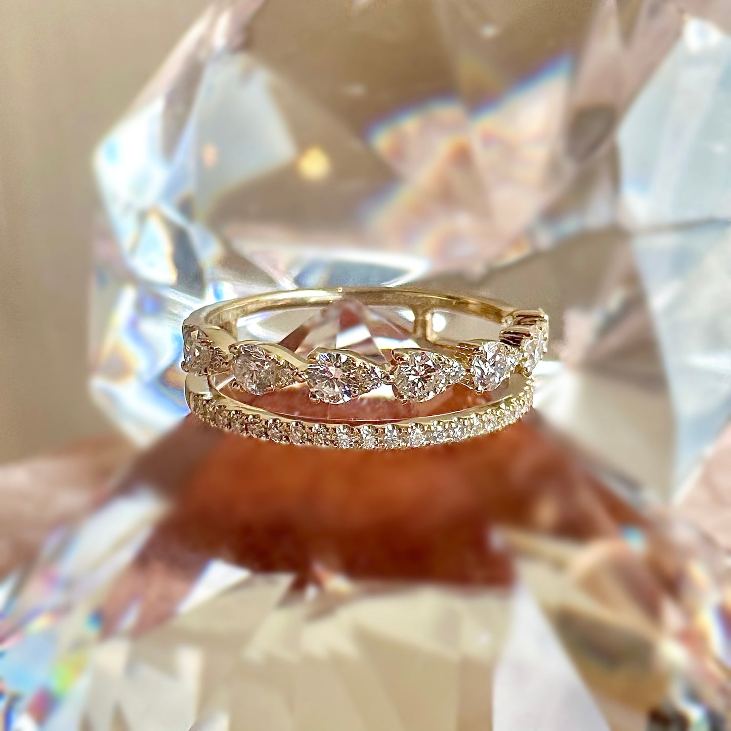 gold and diamond double banded ring on a fake diamond with blurred fake diamond in background