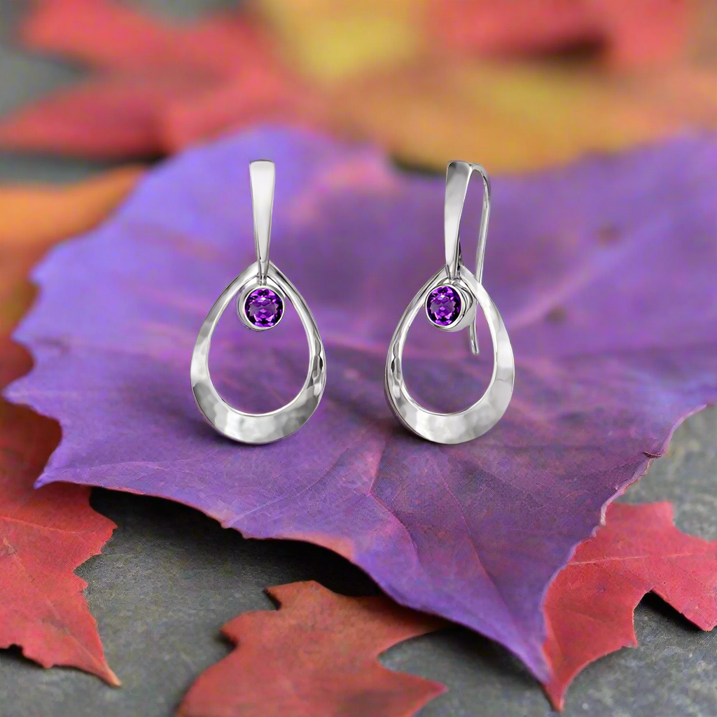 Earrings sitting on a purple leaf, available at plumb silver jewelry store