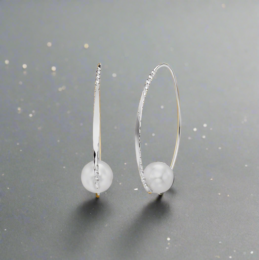 Sterling silver and pearl earrings available at plumb silver jewelry store, resting on a flat surface with a gray backdrop